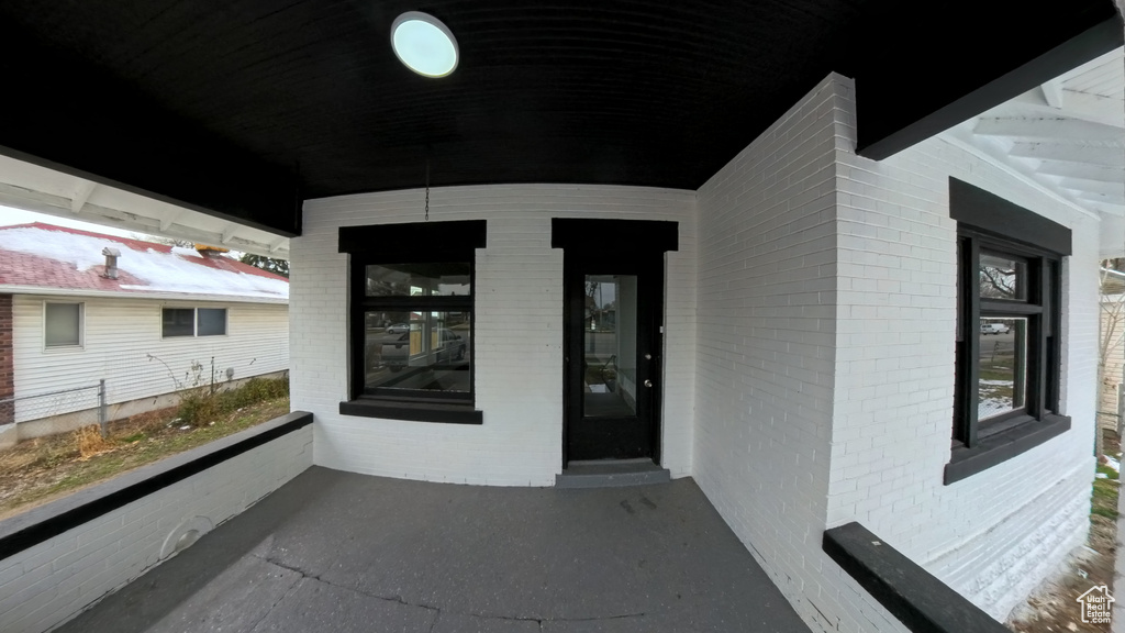 Property entrance featuring covered porch and brick siding