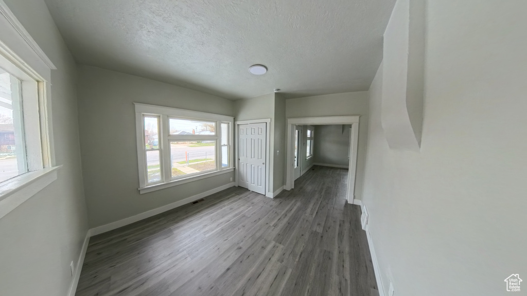 Unfurnished bedroom with baseboards, a textured ceiling, visible vents, a closet, and wood finished floors