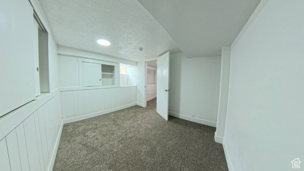 Interior space featuring carpet flooring, baseboards, and a textured ceiling