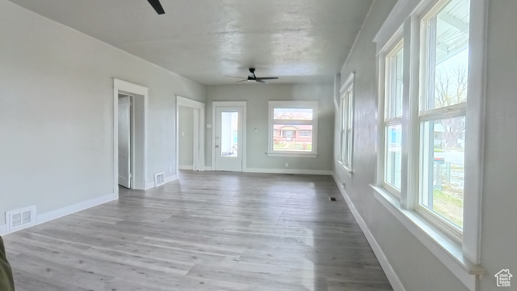 Unfurnished room with visible vents, wood finished floors, ceiling fan, and a healthy amount of sunlight