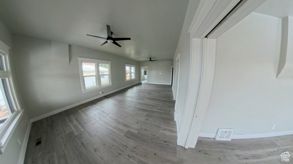 Unfurnished living room featuring a ceiling fan, baseboards, lofted ceiling, and wood finished floors