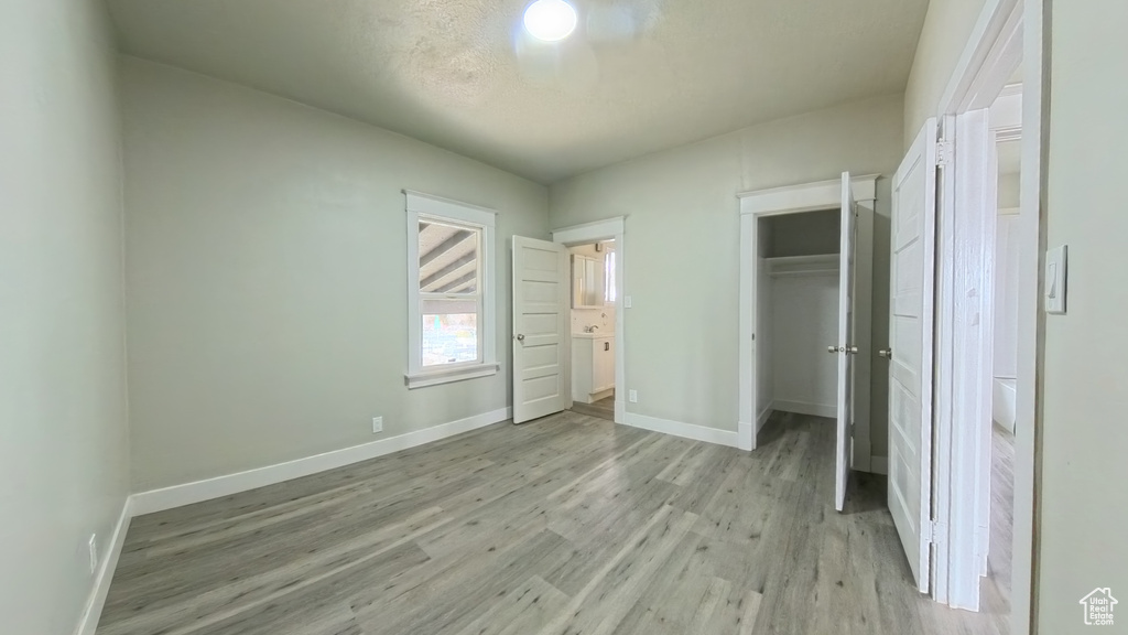 Unfurnished bedroom featuring light wood finished floors, baseboards, a closet, and a spacious closet