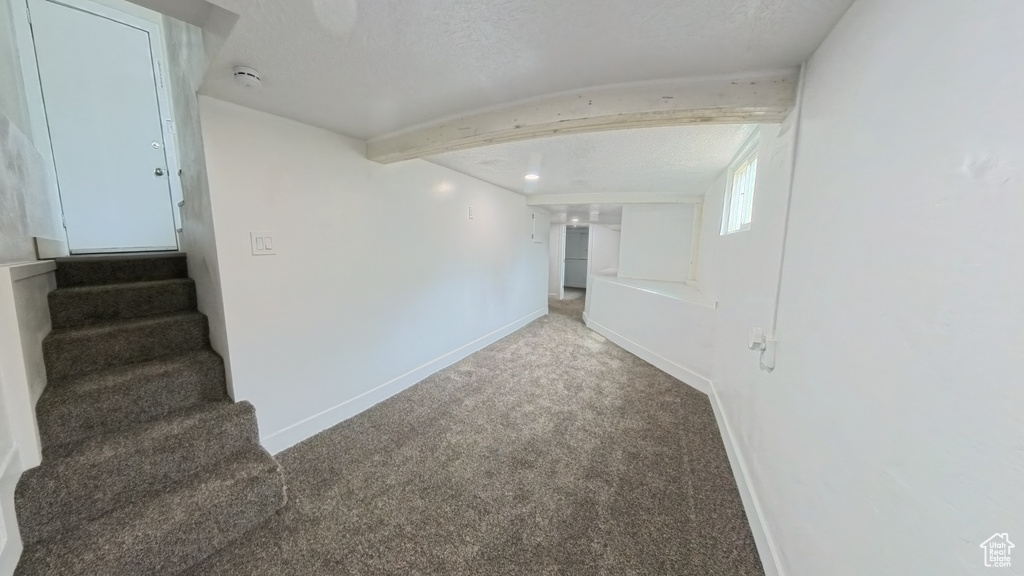 Carpeted spare room with baseboards, stairway, and a textured ceiling