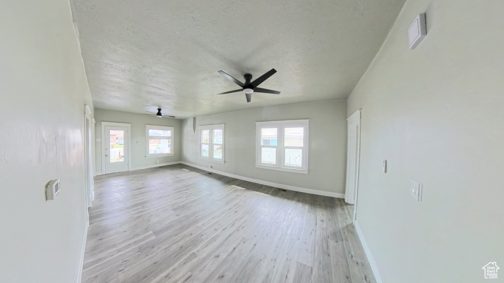 Spare room with baseboards, wood finished floors, ceiling fan, and a textured ceiling