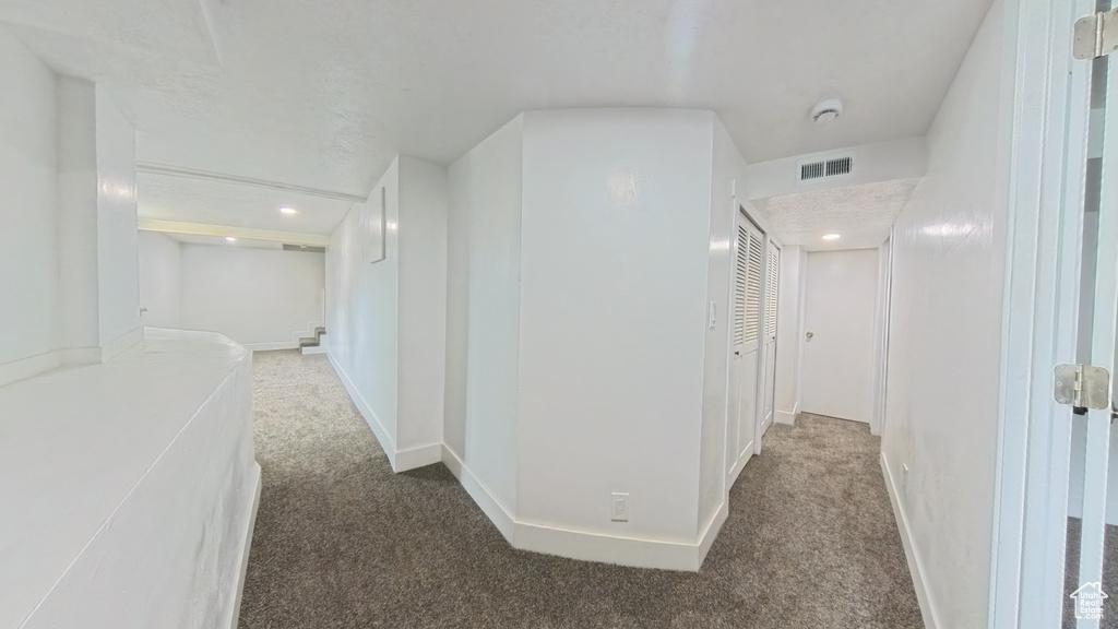 Hall with carpet flooring, baseboards, and visible vents