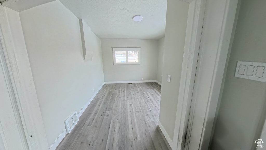 Empty room featuring baseboards, visible vents, light wood-style flooring, and a textured ceiling