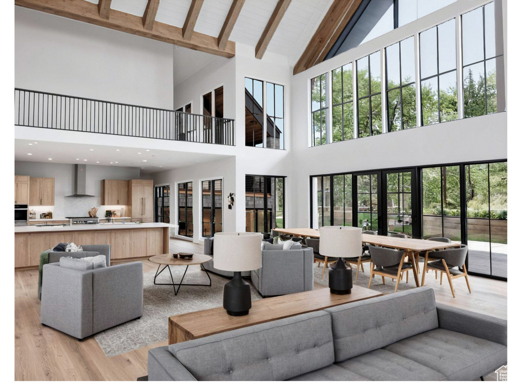 Living area featuring high vaulted ceiling, light wood-type flooring, and beamed ceiling