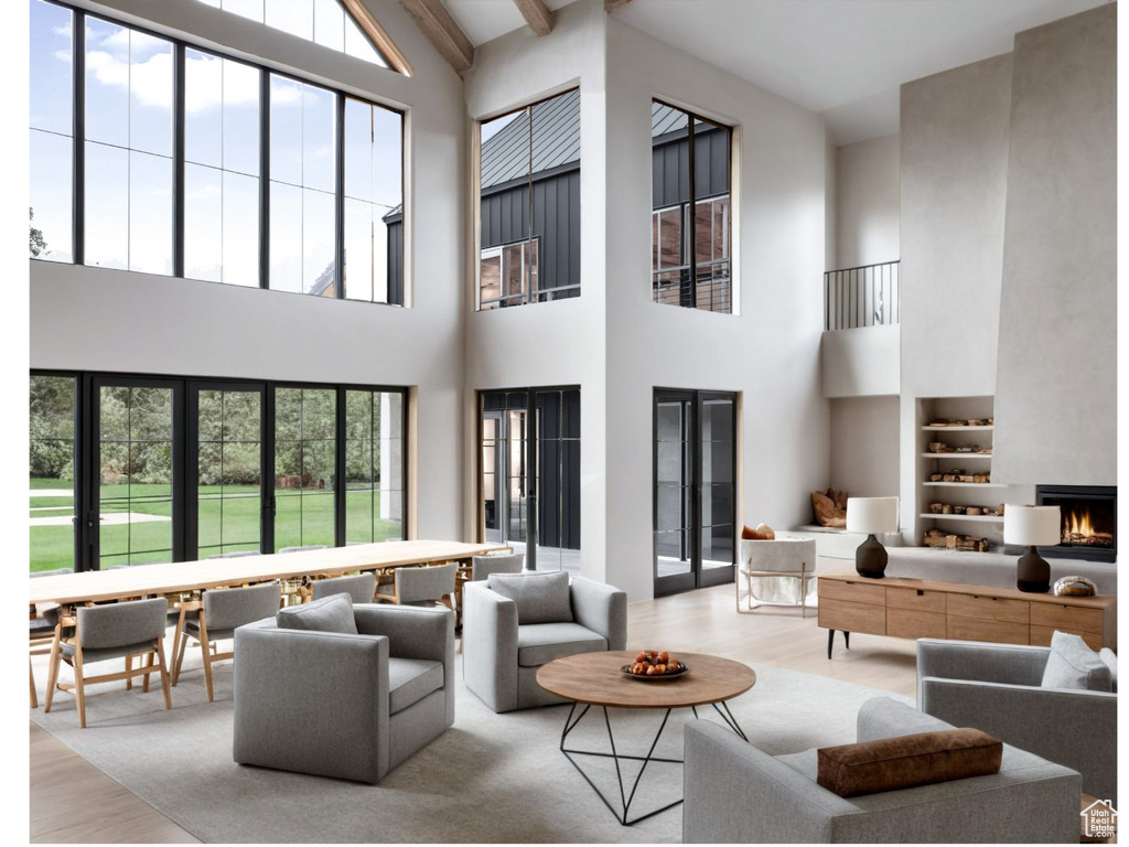 Living room featuring wood finished floors, high vaulted ceiling, plenty of natural light, beam ceiling, and a fireplace