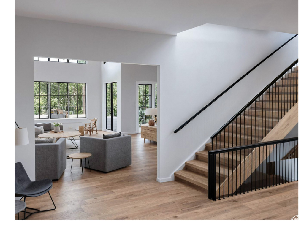 Living area featuring wood finished floors, stairway, a towering ceiling, and baseboards