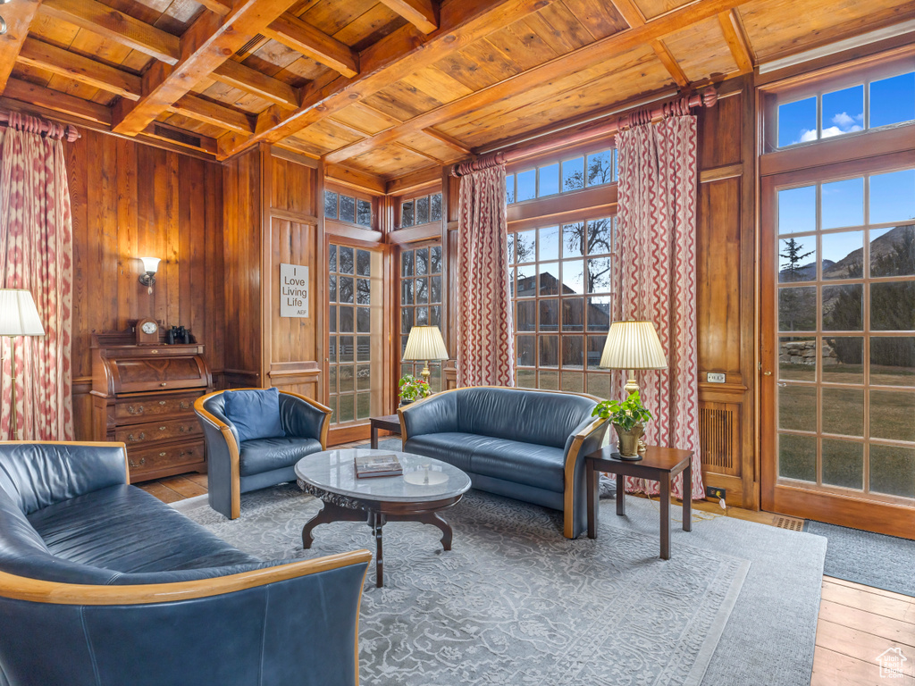 Living area with wooden ceiling with exposed beams, wooden walls, and hardwood / wood-style flooring