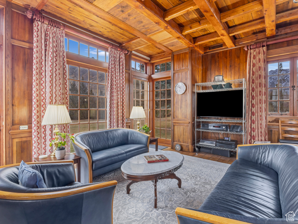 Living area with wooden ceiling with exposed beams, wooden walls, hardwood / wood-style flooring, and coffered ceiling