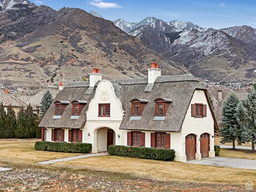 French country home featuring a chimney, stucco siding, a mountain view, and concrete driveway