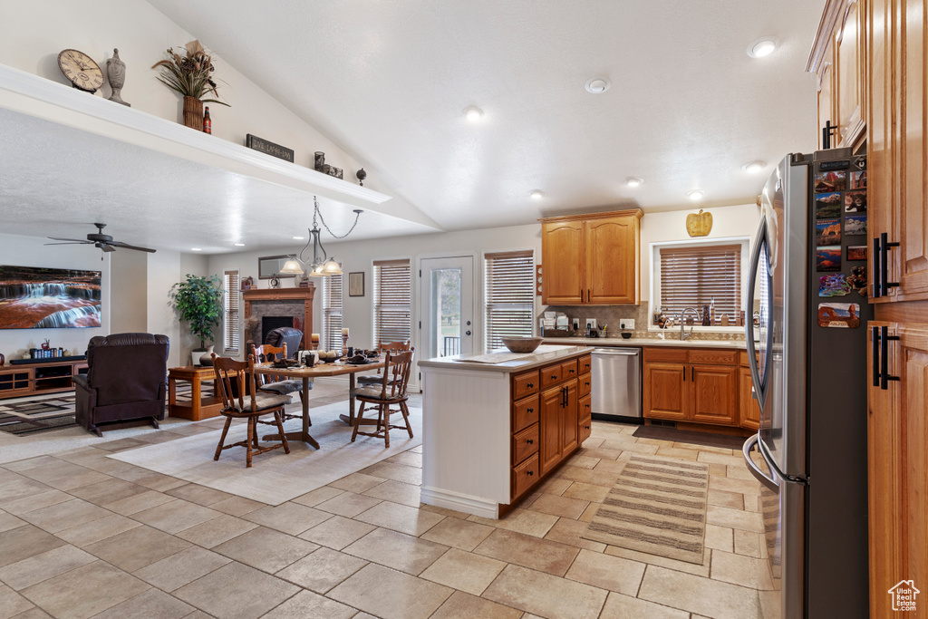 Kitchen featuring a fireplace, light countertops, appliances with stainless steel finishes, open floor plan, and vaulted ceiling