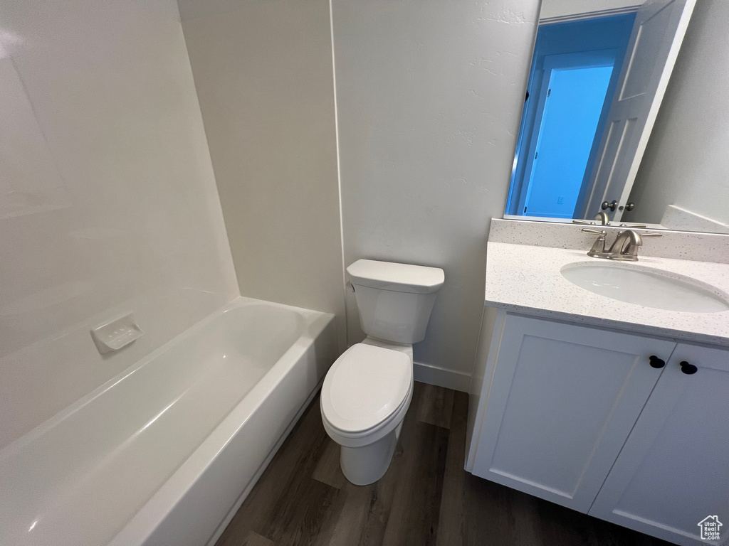 Bathroom with toilet, baseboards, wood finished floors, and vanity