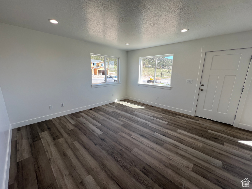 Interior space featuring a textured ceiling, recessed lighting, dark wood finished floors, and baseboards