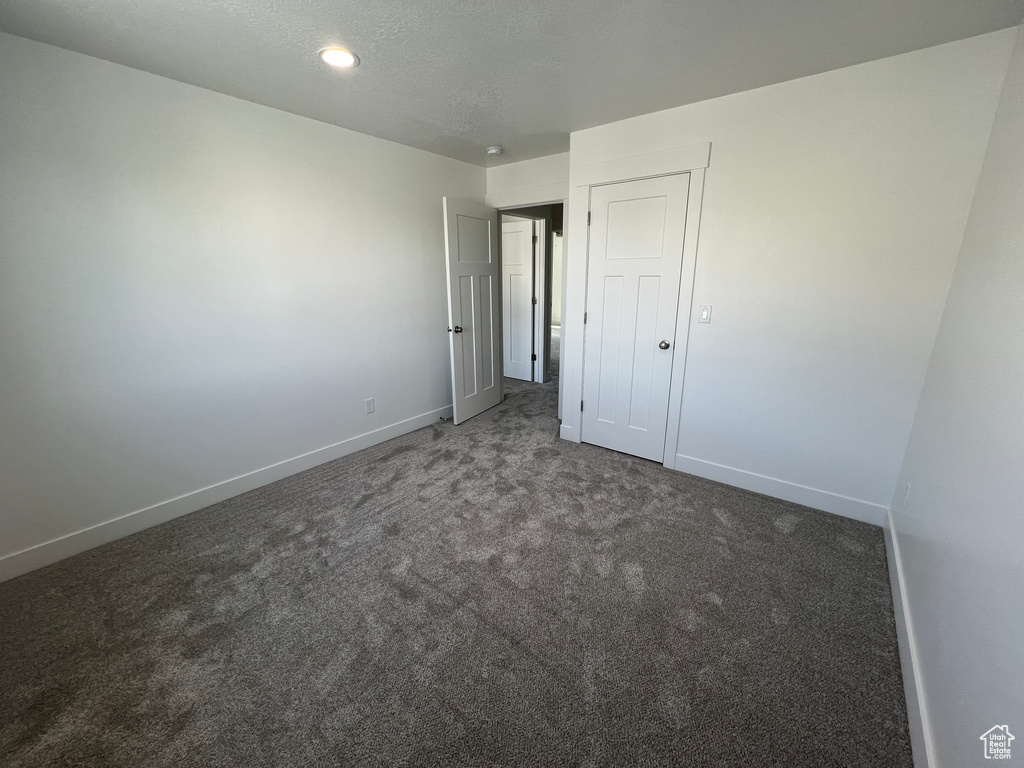 Unfurnished bedroom with carpet, a textured ceiling, and baseboards