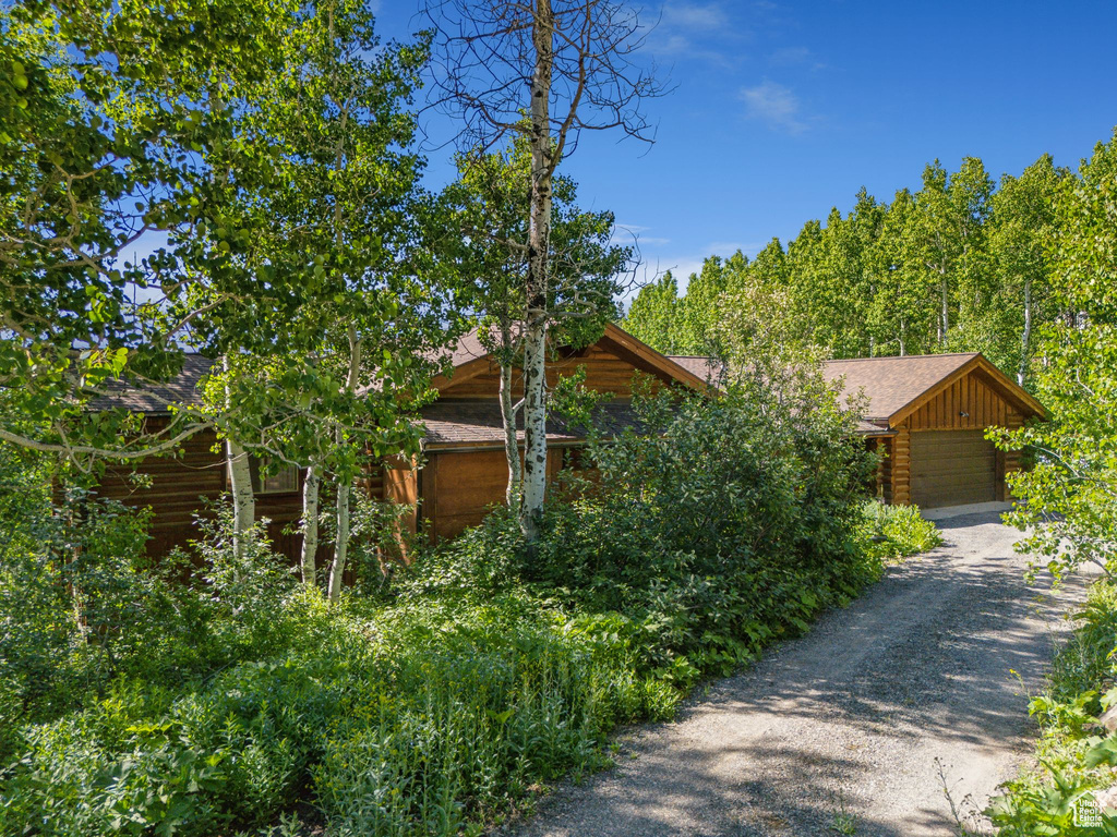 View of front of property with a garage, roof with shingles, and driveway