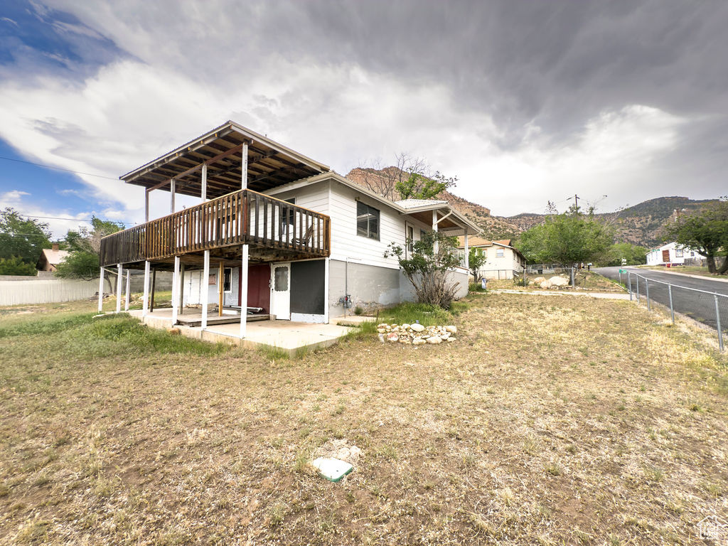 Rear view of property with a deck with mountain view, a patio, and a fenced backyard