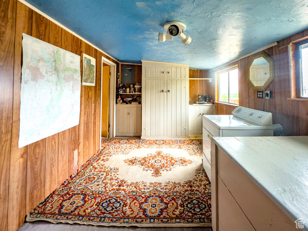 Laundry area featuring wood walls and washer and clothes dryer