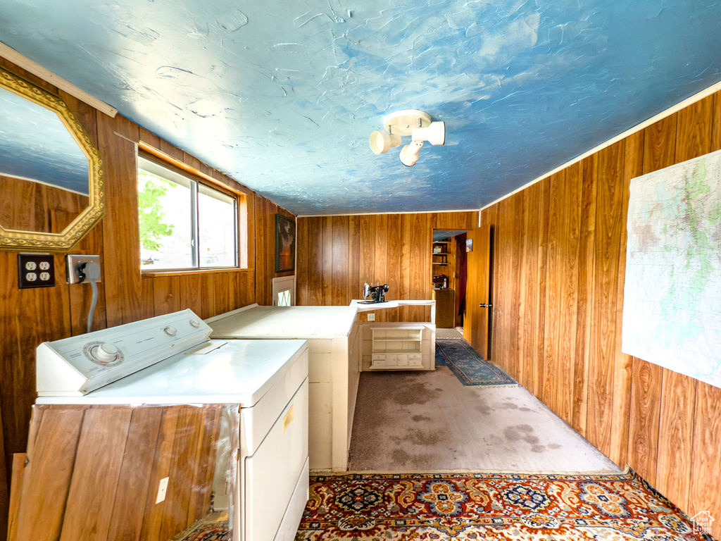 Washroom featuring washing machine and clothes dryer, wooden walls, and carpet