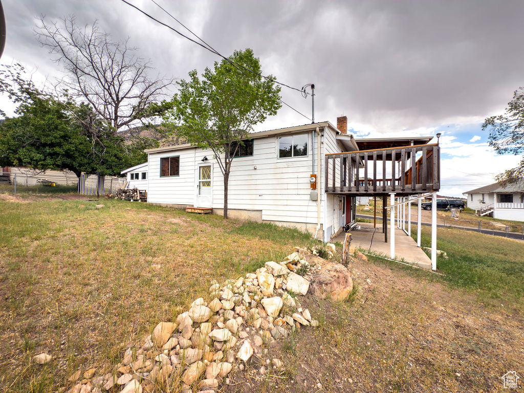 Back of house with a deck, a chimney, and a patio
