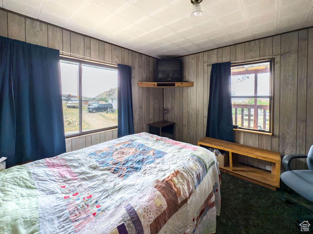 Carpeted bedroom featuring wooden walls