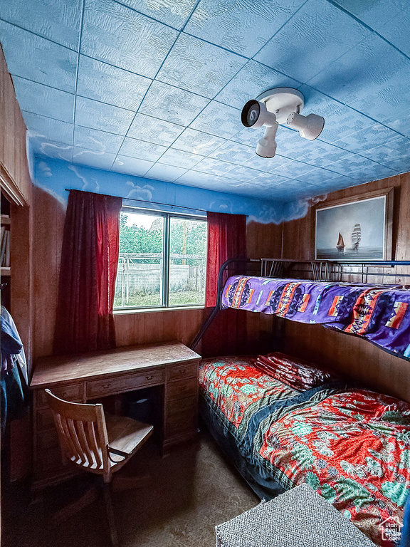 Bedroom featuring carpet flooring and wood walls