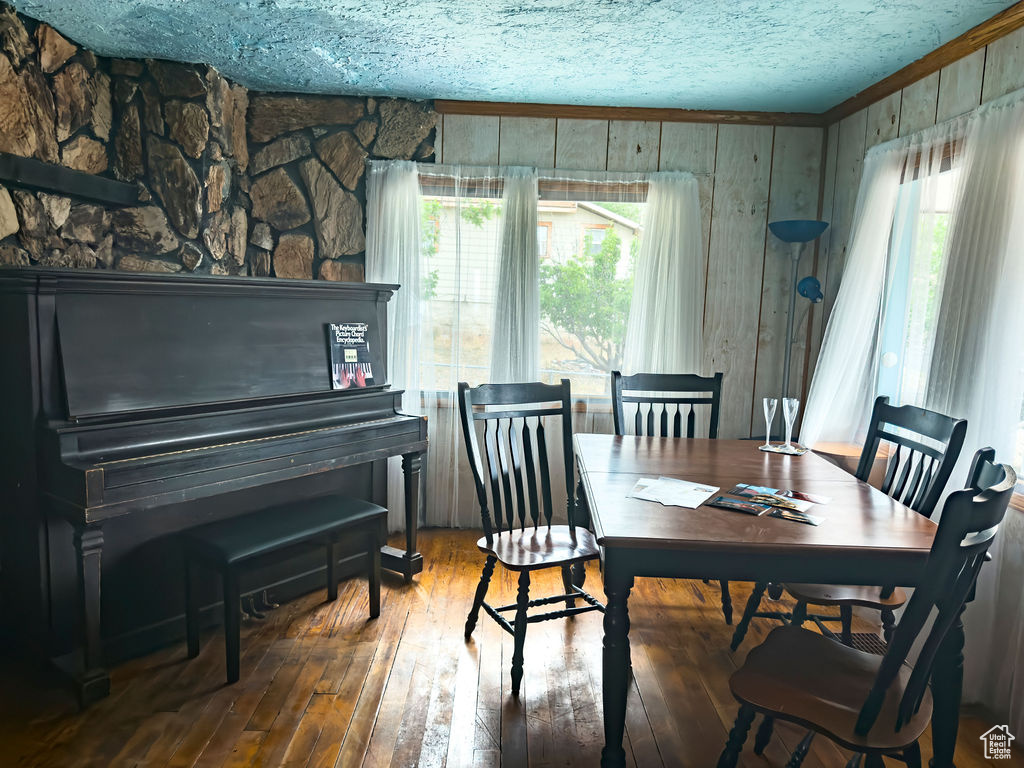 Dining space featuring hardwood / wood-style floors, wooden walls, and a textured ceiling