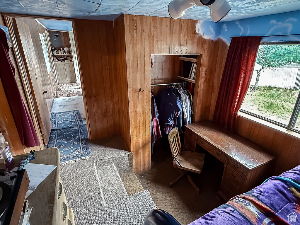 Bedroom with wood walls, carpet floors, and a closet