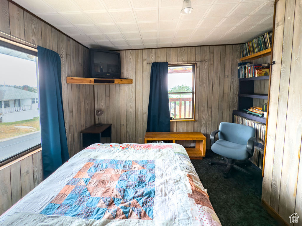 Carpeted bedroom featuring wooden walls
