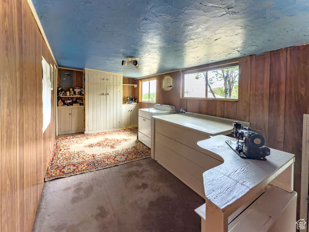 Miscellaneous room featuring wood walls, washing machine and dryer, and light colored carpet