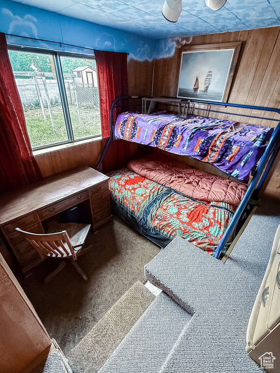 Bedroom with wood walls and carpet