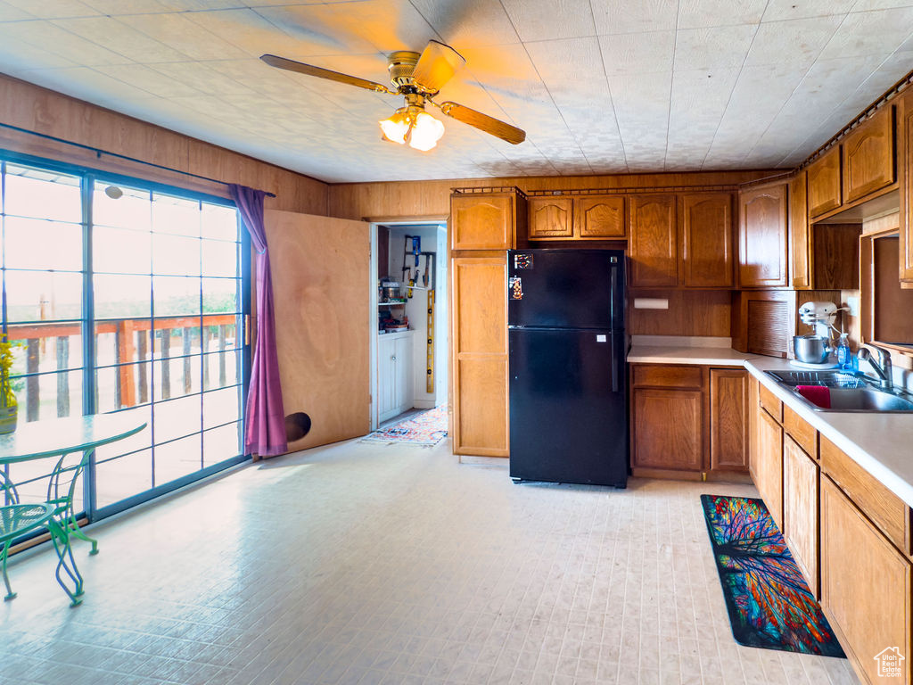 Kitchen with freestanding refrigerator, ceiling fan, brown cabinetry, and light countertops