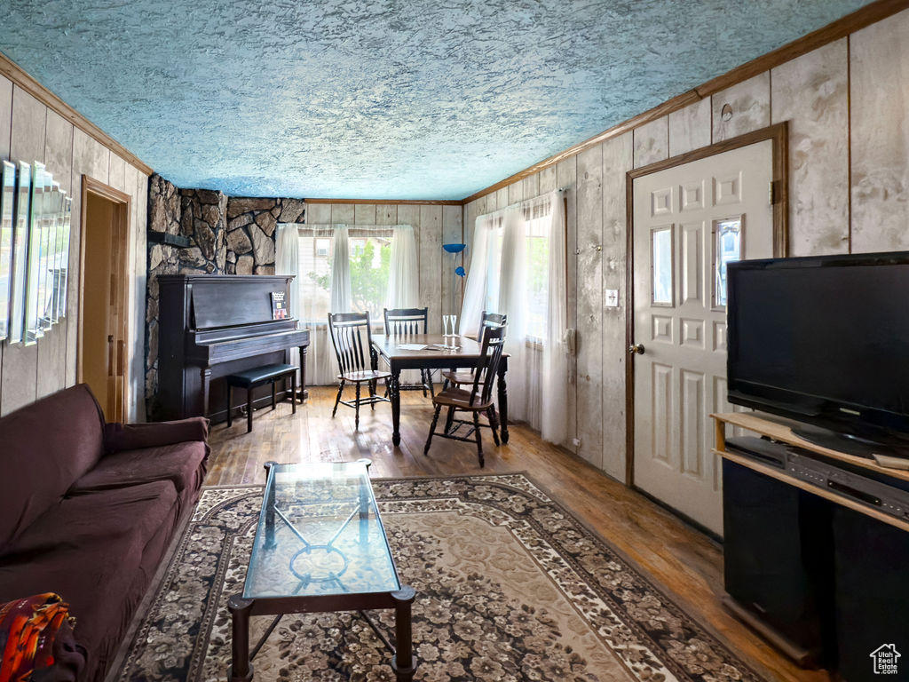 Living area with ornamental molding, wood walls, wood finished floors, and a textured ceiling