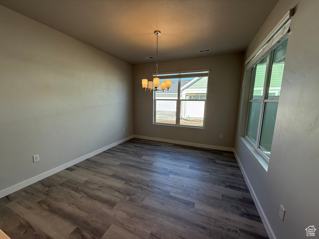 Unfurnished dining area featuring visible vents, baseboards, a chandelier, and dark wood-type flooring
