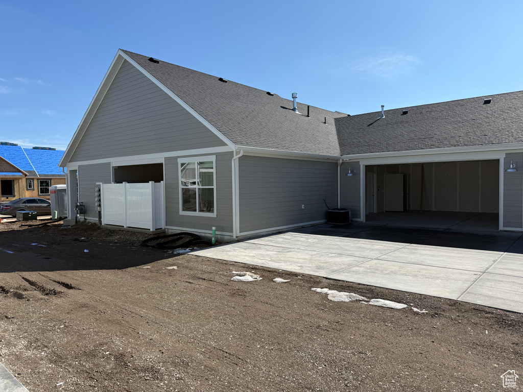 Rear view of house with driveway and a shingled roof