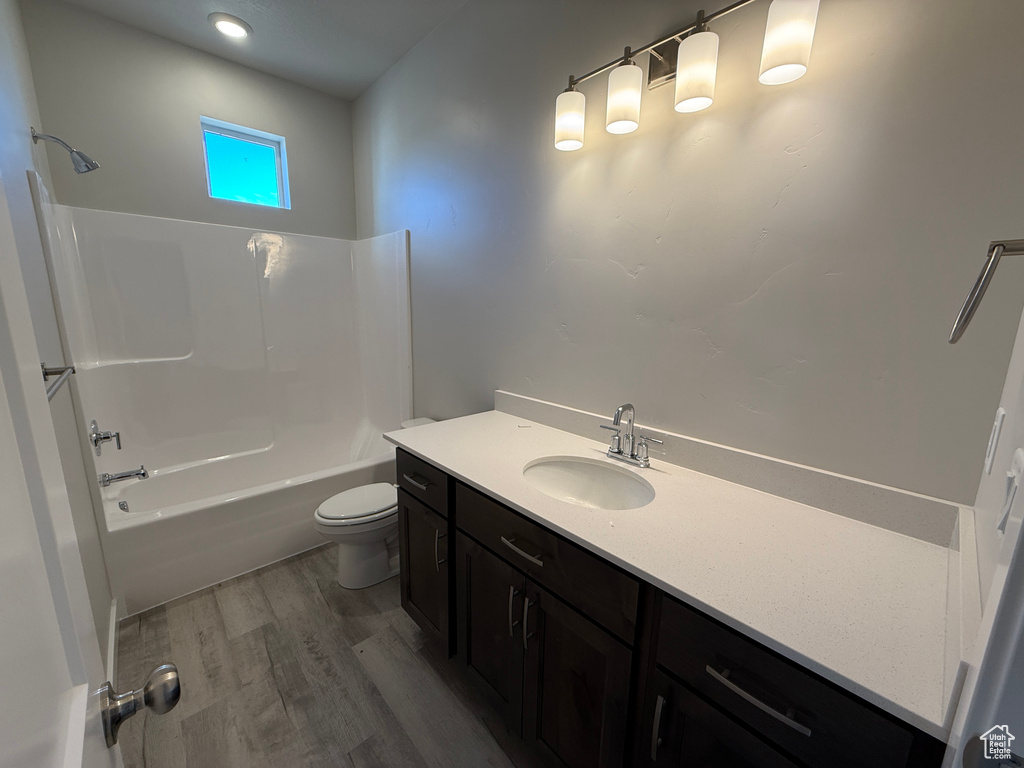 Bathroom with tub / shower combination, vanity, toilet, and wood finished floors