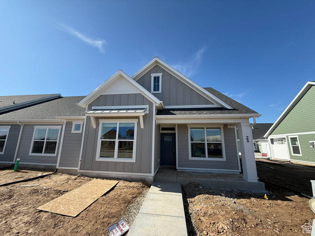 View of front facade featuring board and batten siding and roof with shingles