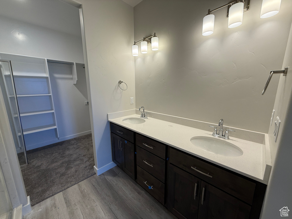 Full bathroom with wood finished floors, a spacious closet, double vanity, and a sink