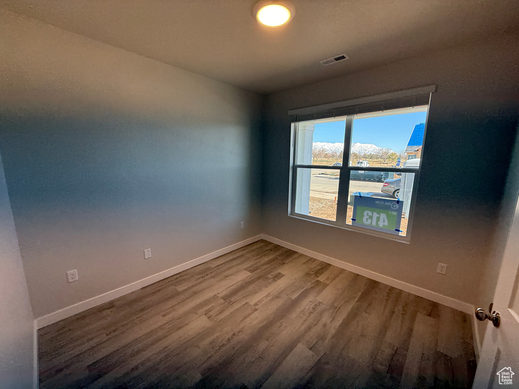 Unfurnished room with baseboards, visible vents, and wood finished floors