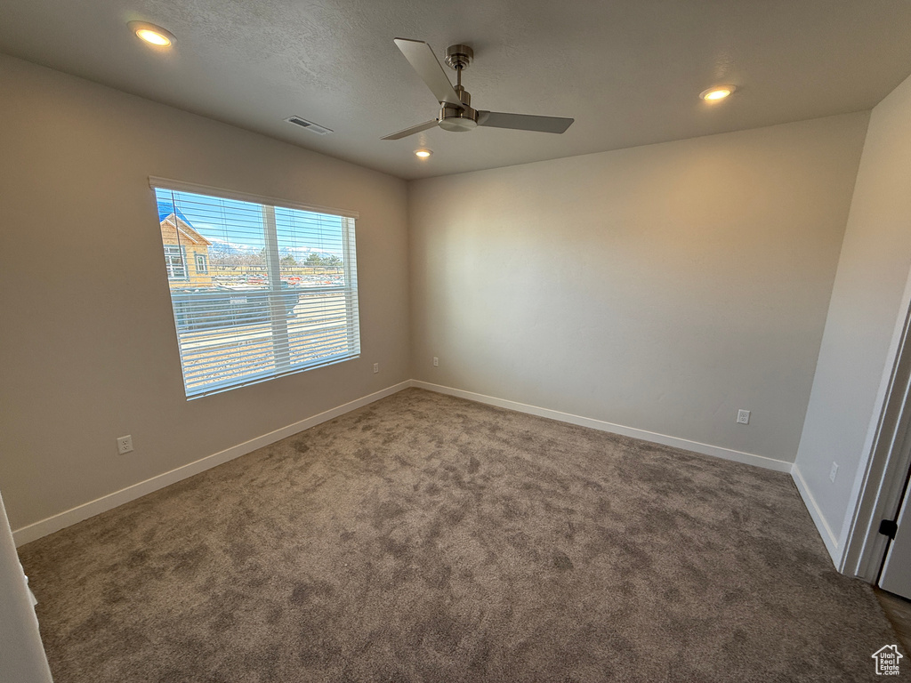 Spare room featuring visible vents, baseboards, dark carpet, and recessed lighting