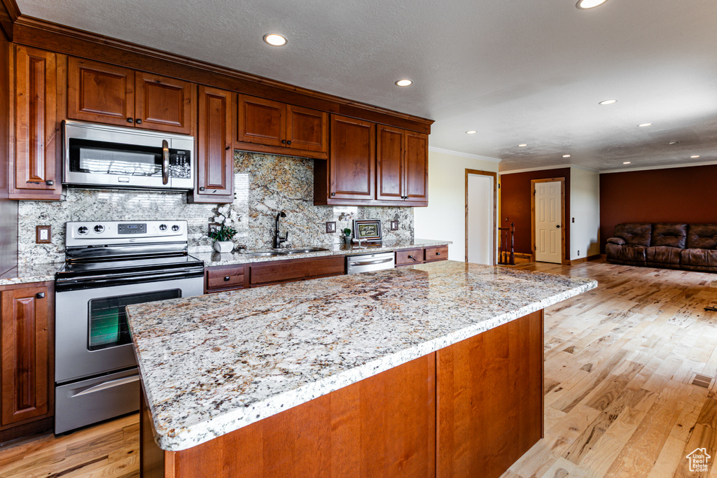 Kitchen featuring light stone countertops, tasteful backsplash, stainless steel appliances, and a sink