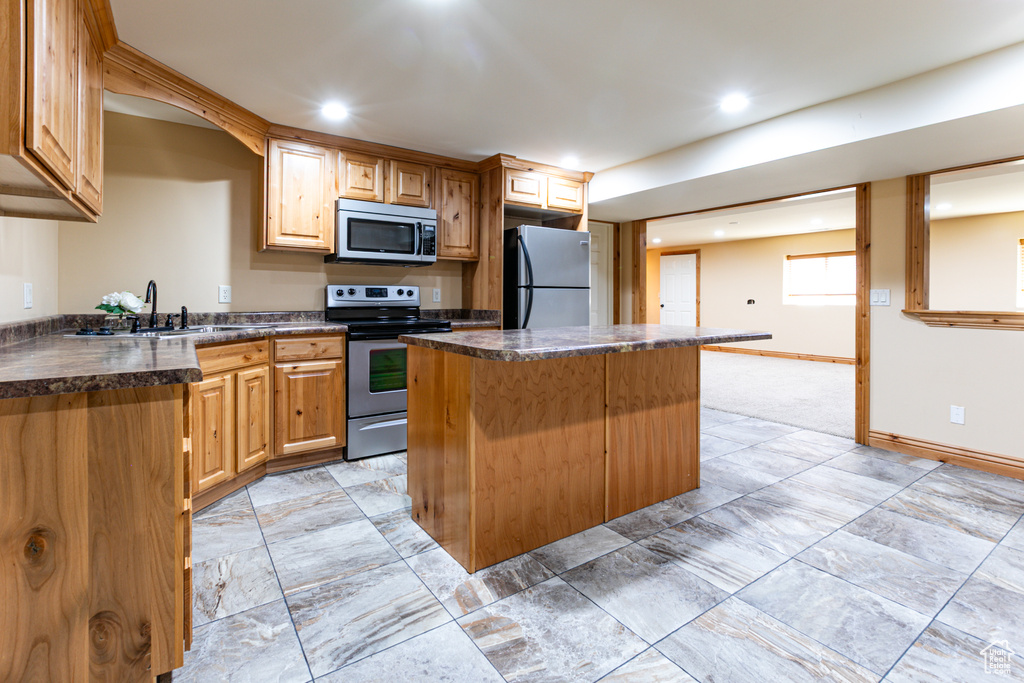 Kitchen featuring stainless steel appliances, a center island, dark countertops, a sink, and recessed lighting