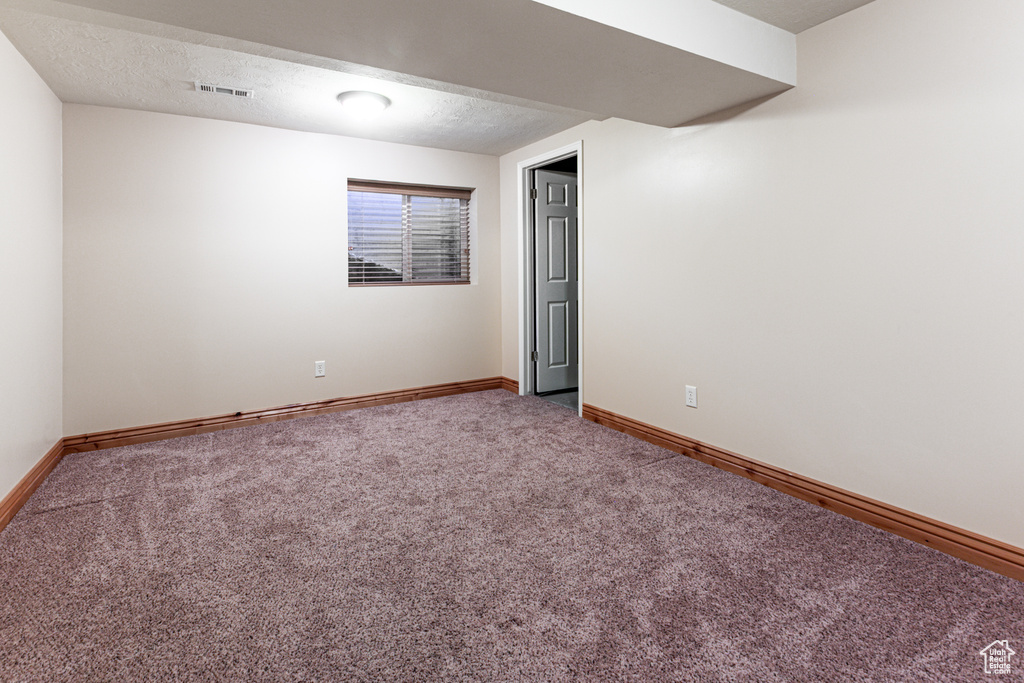 Basement with carpet, baseboards, and a textured ceiling