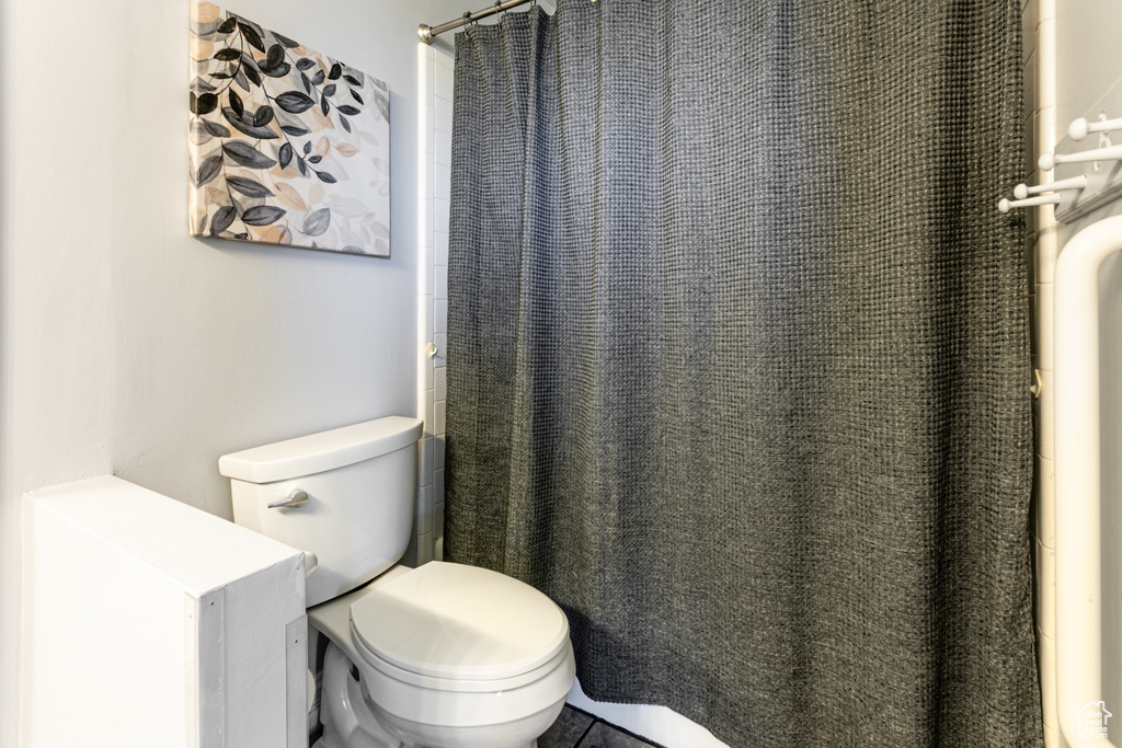 Bathroom featuring toilet and curtained shower