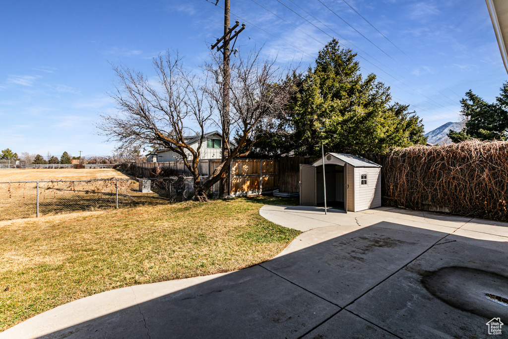 View of yard with a storage shed, a fenced backyard, an outbuilding, and a patio