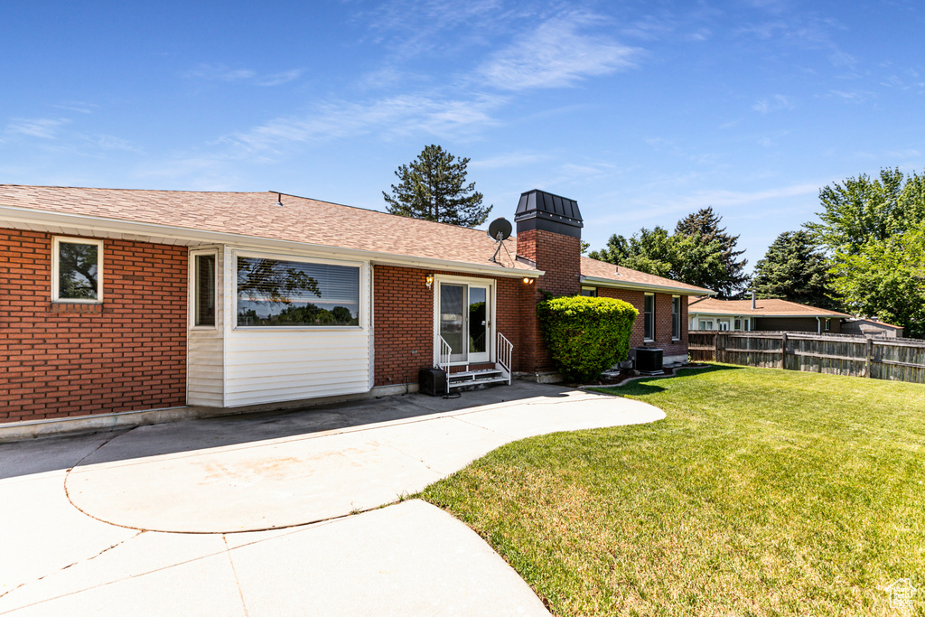 View of front facade with entry steps, brick siding, a patio, and a chimney