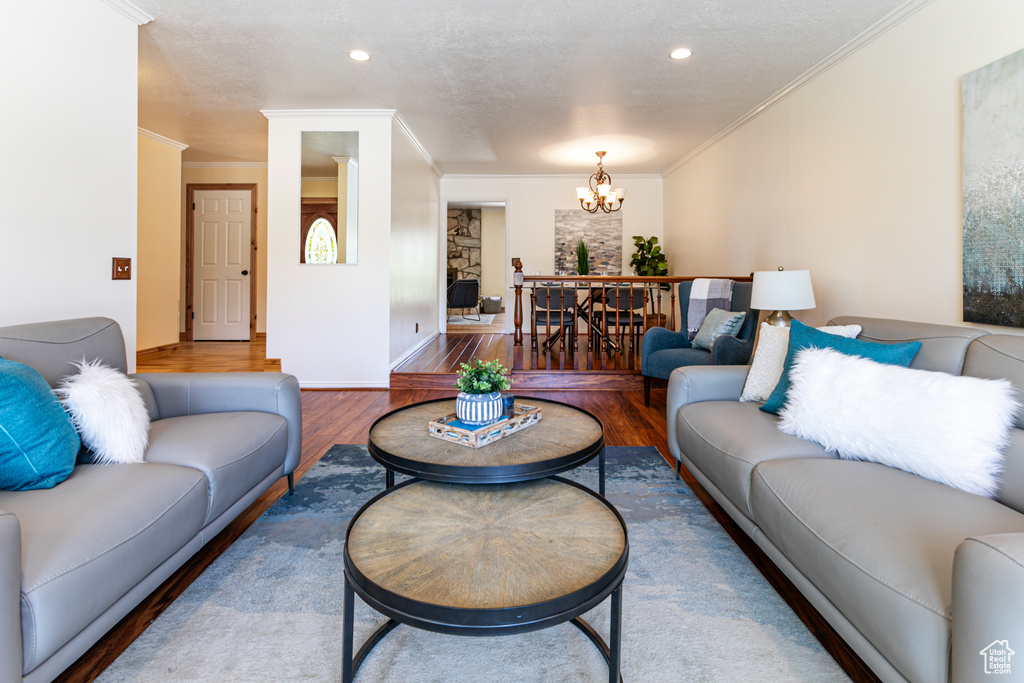 Living area with wood finished floors, a chandelier, crown molding, recessed lighting, and baseboards