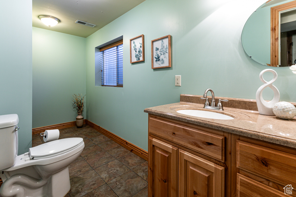 Bathroom featuring toilet, vanity, and baseboards