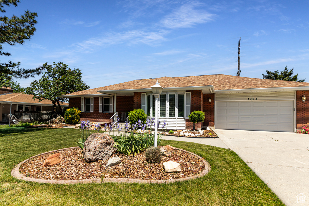 Ranch-style house featuring brick siding, an attached garage, driveway, a front lawn, and a shingled roof